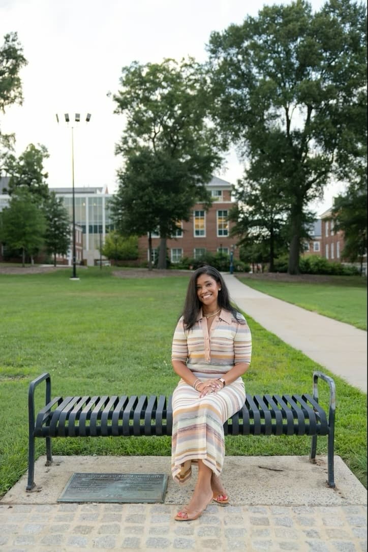 Ashley sitting alone on a bench on the University of Maryland campus.