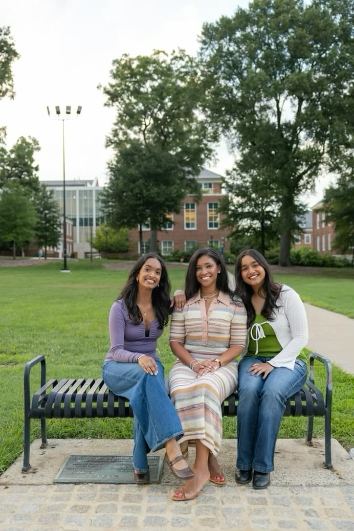 Srinidhi, Ashley and Avishi on the bench, arms around each other.