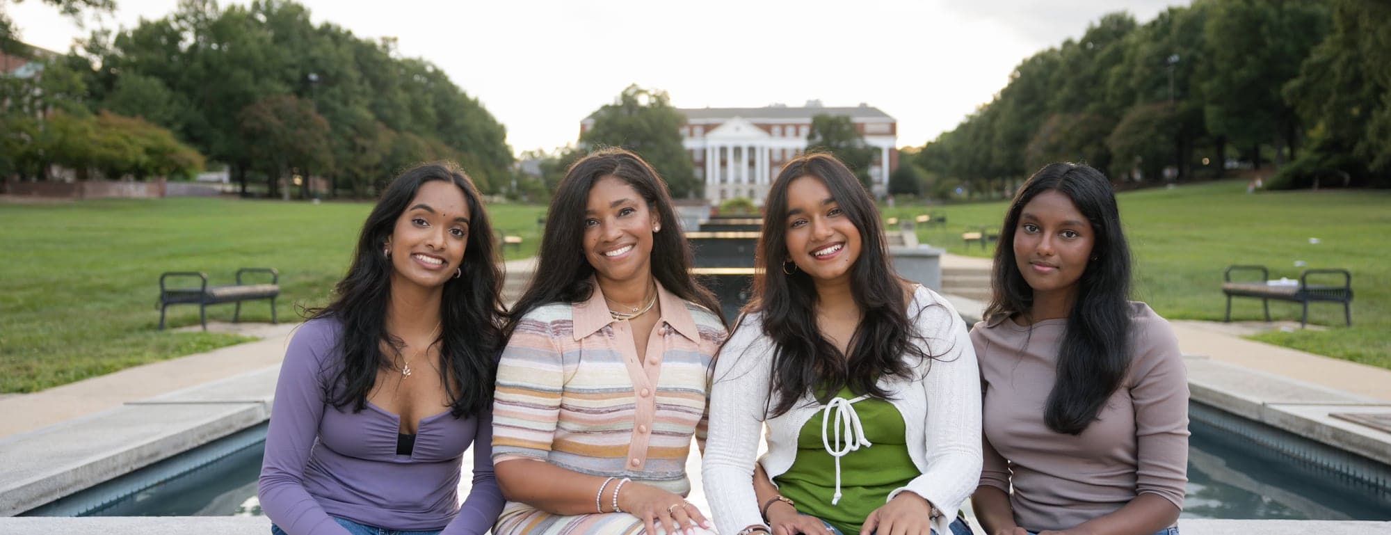 Srinidhi, Ashley, Avishi and Akhila sitting along the edge of the fountain at the University of Maryland.